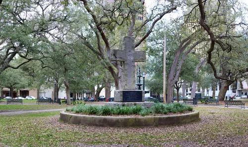 The granite cross honoring Bienville stands amid large trees