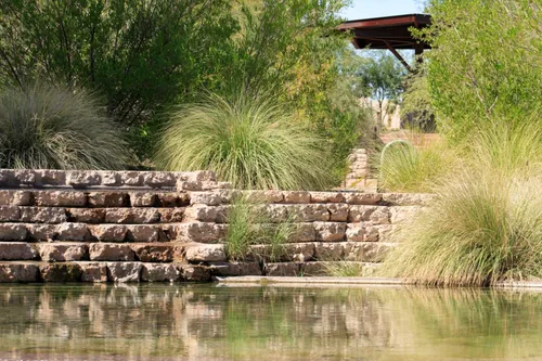 Natural stone wall and ornamental grasses frame the pond edge