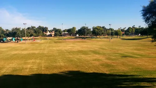 The park's wide open grassy field under clear blue Arizona skies