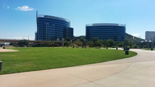 Pathway alongside green lawns with modern buildings in the background
