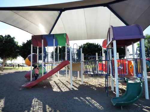 Playground equipment under a protective shade canopy