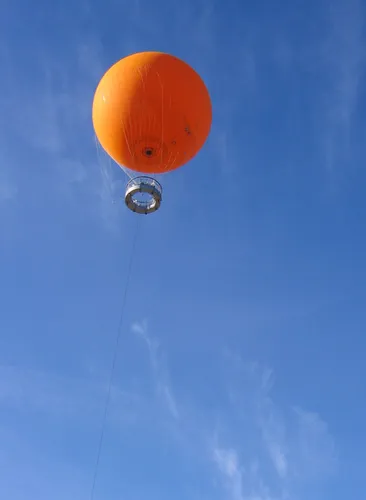 The Great Orange Balloon floating against a clear blue sky