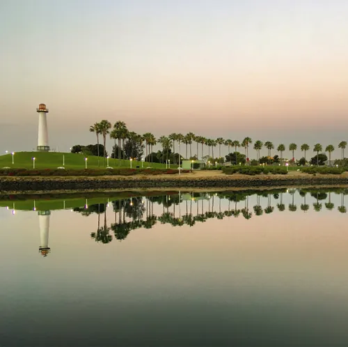 Reflections of palm trees and lighthouse in still waters