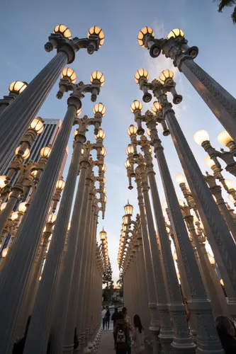 Looking up through the Urban Light installation at dusk as the lamps begin to glow