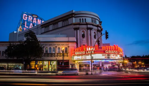 Historic Grand Lake Theatre illuminated at dusk across from the park