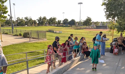 Families gather for an event with the sports fields visible behind