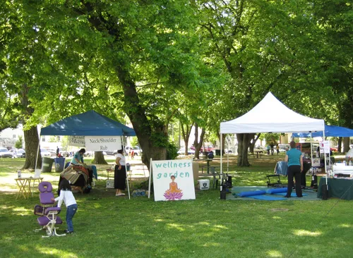 Park event with tents and vendors under lush green trees