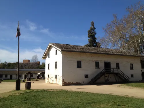 White adobe buildings with external staircase next to flagpole