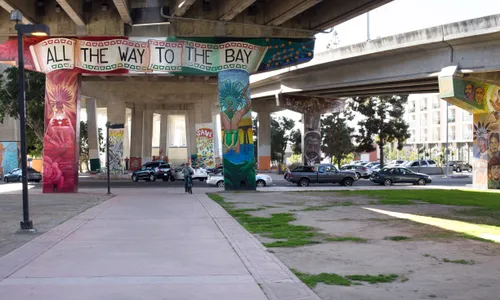 Walkway between green spaces underneath one of multiple bridges