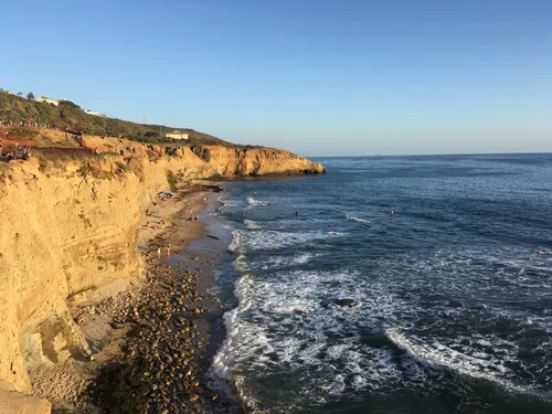 Dramatic sandstone cliffs with waves rolling onto the narrow beach below