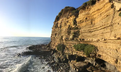 Towering layered cliff face standing against the crashing surf
