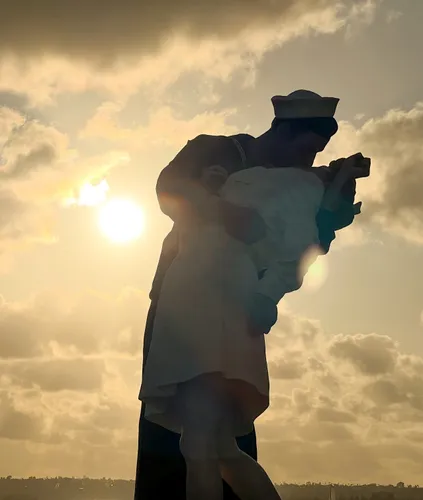 Unconditional Surrender statue silhouetted against a golden sunset sky