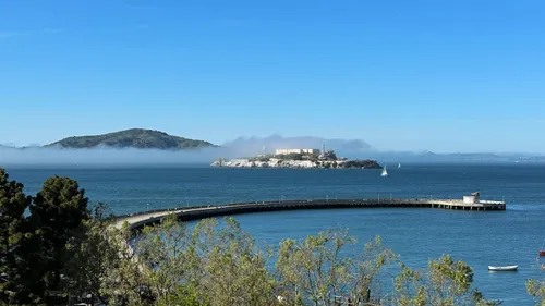 The arc-shaped Aquatic Park Pier extends into the bay with Alcatraz Island in the distance