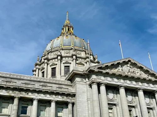 The ornate dome of San Francisco City Hall catches sunlight against a blue sky