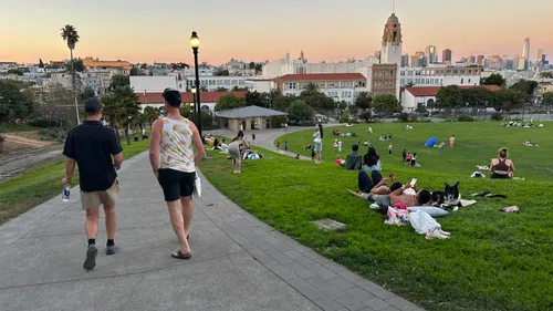 Visitors enjoying the park's hillside on a warm evening