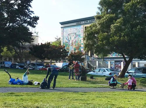 Visitors relax on the grassy area at Precita Park