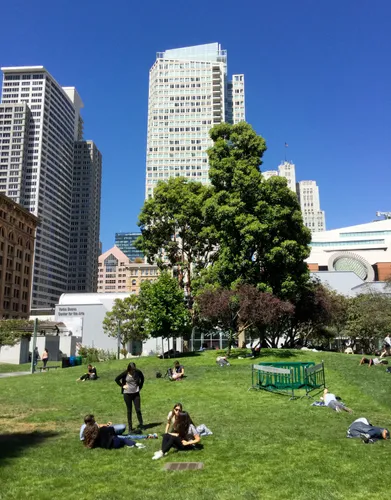 Visitors relax on the grass with San Francisco's skyline rising behind