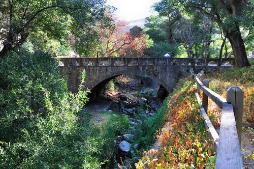 Stone bridge arches over Upper Penitencia Creek amid autumn foliage