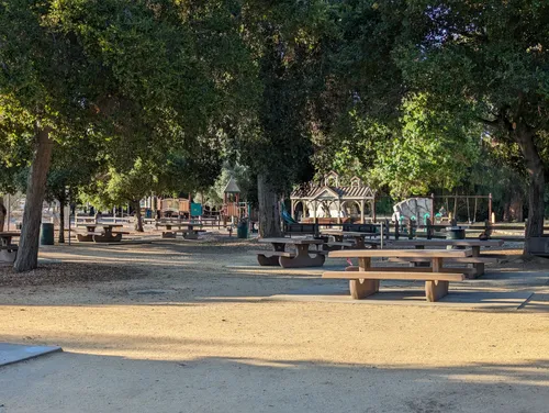 Picnic tables with benches offer seating underneath trees