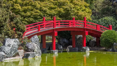 Red bridge arches over picturesque pond
