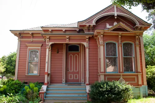 Beautifully restored pink Victorian building with ornate trim details