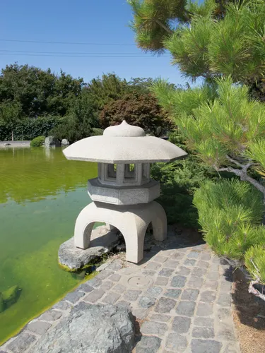 Traditional stone lantern sits beside calm water in Japanese Friendship Garden