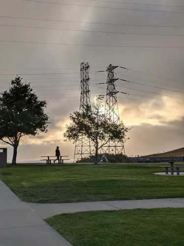 Transmission towers beyond the park's lawns on a cloudy morning