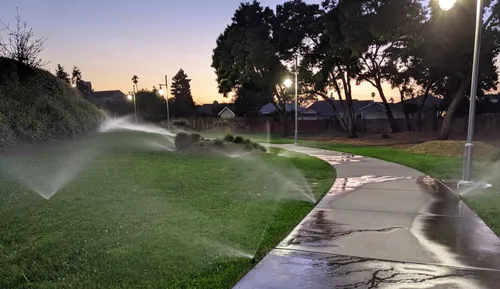 Sprinklers water the lawn along the western walking path