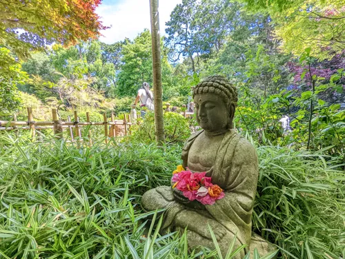 Stone Buddha statue adorned with red floral offerings