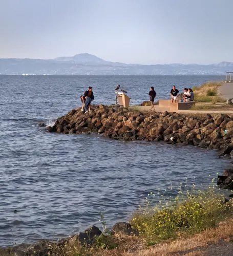 Visitors enjoying the rocky jetty with Mount Diablo visible in the far distance