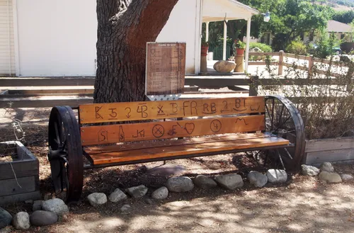 Rustic wooden bench featuring traditional cattle brands