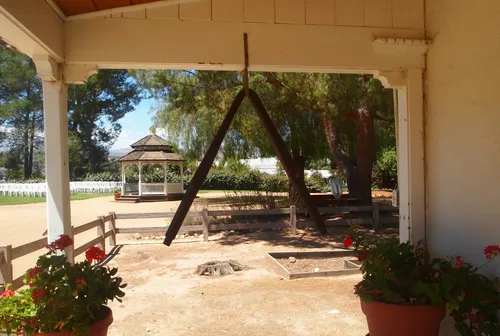 Shaded porch area with dinner bell and potted plants