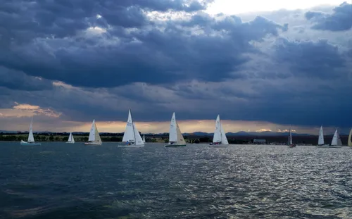Sailboats glide across Cherry Creek Reservoir under storm clouds