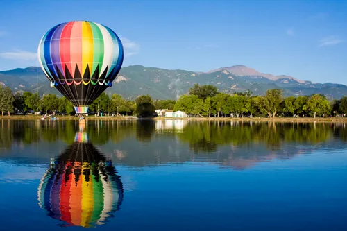 Vibrant rainbow balloon perfectly reflected in Prospect Lake