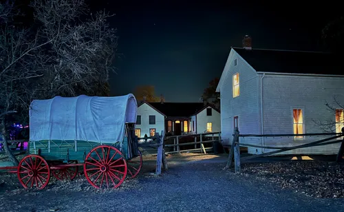 Nighttime view of historic structures with an old wagon stationed nearby