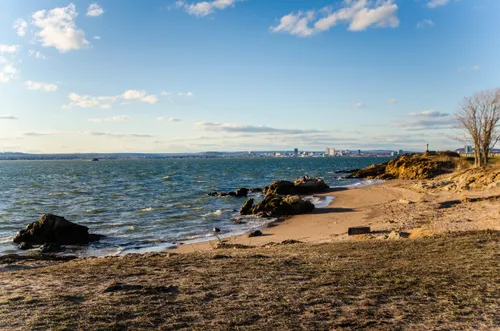 Shoreline where water meets sand and rocky outcroppings on a windy day