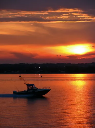 Sunset casts orange glow over boat on the water