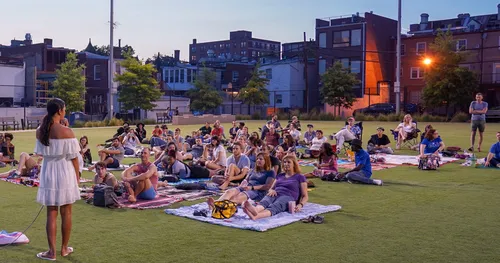 An evening gathering on the lawn with city buildings in the background