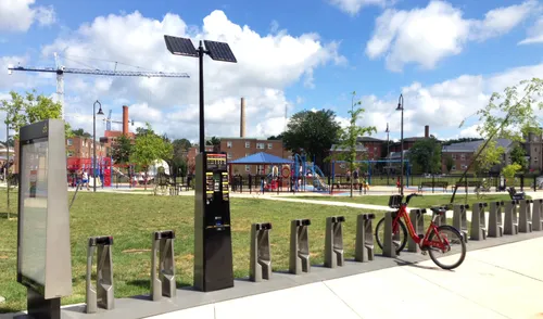 Bikeshare station at the park's south entrance with the playground area visible behind