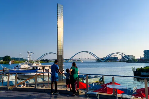Visitors enjoy waterfront views with the Frederick Douglass Memorial Bridge visible in the distance