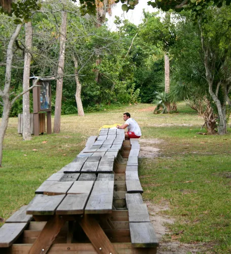 A visitor sits at the end of a long row of picnic tables