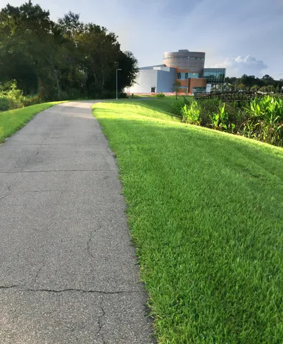 Paved walking trail toward Cade Museum alongside manicured green lawn