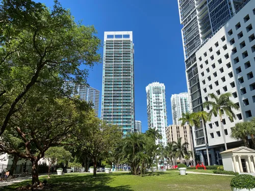 High-rises of Miami's Financial District are visible beyond Mary Brickell Park's tree-lined grounds