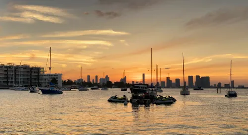 Boats in Biscayne Bay with the Miami skyline silhouetted against a warm sunset sky