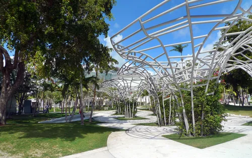 White sculptural canopies weave between palm trees in this urban oasis