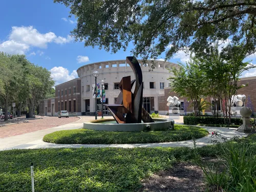 A sculpture stands near the curved facade of the Orlando Museum of Art