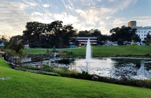 Fountain jets up from Smokey Hollow Pond as evening falls over Cascades Park