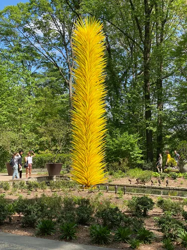 Visitors admire the Radiant Yellow Icicle Tower artpiece in the Glade Garden
