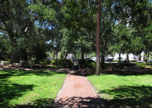 A shaded brick pathway through the square's tranquil green space