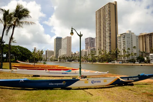 Outrigger canoes rest on the grass next to the boat launch